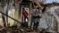 A woman holds food items found as she stands outside her house which was destroyed by a Russian drone attack in a residential neighborhood, in Zaporizhzhia, Ukraine, on March 28, 2024.