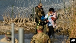 FILE - Migrants are taken into custody by officials at the Texas-Mexico border, in Eagle Pass, Texas, Jan. 3, 2024.