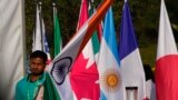 A worker carries Indian national flag to place it with those of other participating countries at the opening session of the G20 foreign ministers meeting, in New Delhi, India, March 2, 2023.