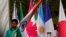 A worker carries Indian national flag to place it with those of other participating countries at the opening session of the G20 foreign ministers meeting, in New Delhi, India, March 2, 2023.