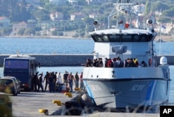 FILE - Migrants disembark from a Greek coast vessel after a rescue operation, at the port of Mytilene, on the northeastern Aegean Sea island of Lesbos, Greece, Aug. 28, 2023.