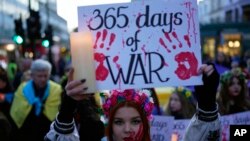 A Ukrainian supporter holds a placard to mark the one-year anniversary of the Russian invasion of Ukraine, as people march to the Russian Embassy, in London.