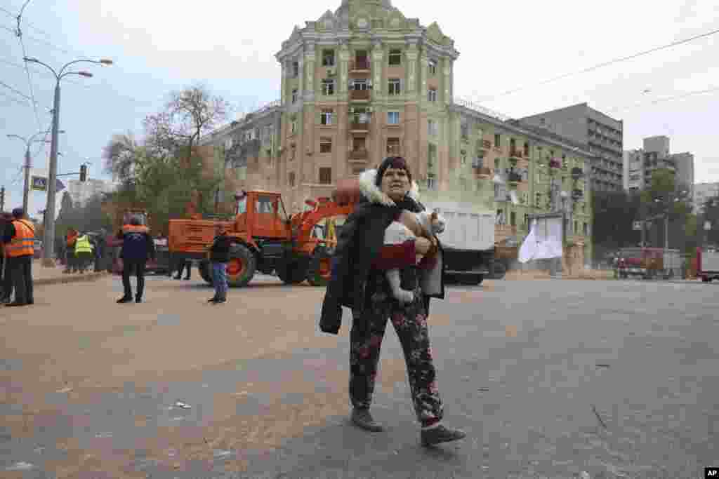 A local resident carries a cat as she passes by an apartment building damaged in the Russian rocket attack in central Kharkiv, Ukraine.