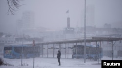 A person stands near a bus station amid heavy snowfall in Randers, Denmark, Jan. 3, 2024. 