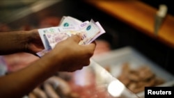 A customer pays for pork meat in a local market, in Buenos Aires, Argentina March 14, 2023. Argentina's annual inflation rate tore past 100% in February.