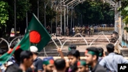 Military and paramilitary personnel stand guard as protesters block the road in front of the former residence of Sheikh Mujibur Rahman, father of the ousted Prime Minister Sheikh Hasina, on his death anniversary in Dhaka, Bangladesh, Aug. 15, 2024.