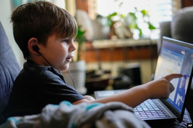 Phoenix Blalack, 6, works with a tutor on his laptop in his Indinapolis home, Tuesday, March 7, 2023. (AP Photo/AJ Mast)