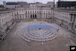 Sebuah karya berjudul 'Whorled (Here After Here After Here)' karya seniman India Jitish KallatIn, berdiri di tengah, di Somerset House di London, 16 Februari 2023. (Foto: AP)