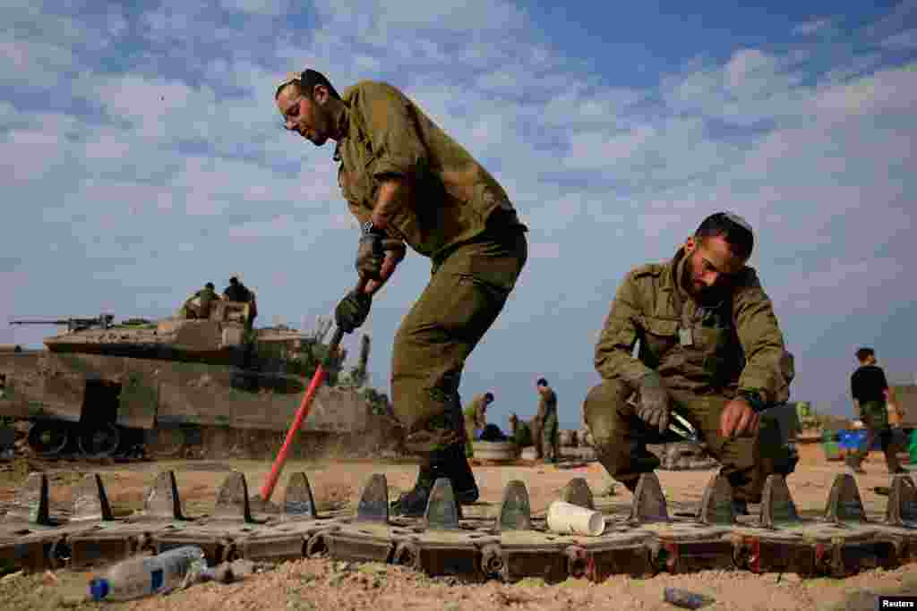 Israeli soldiers work to repair tanks amid the ongoing conflict between Israel and the Palestinian Islamist group Hamas, near the Israel-Gaza border, in southern Israel.