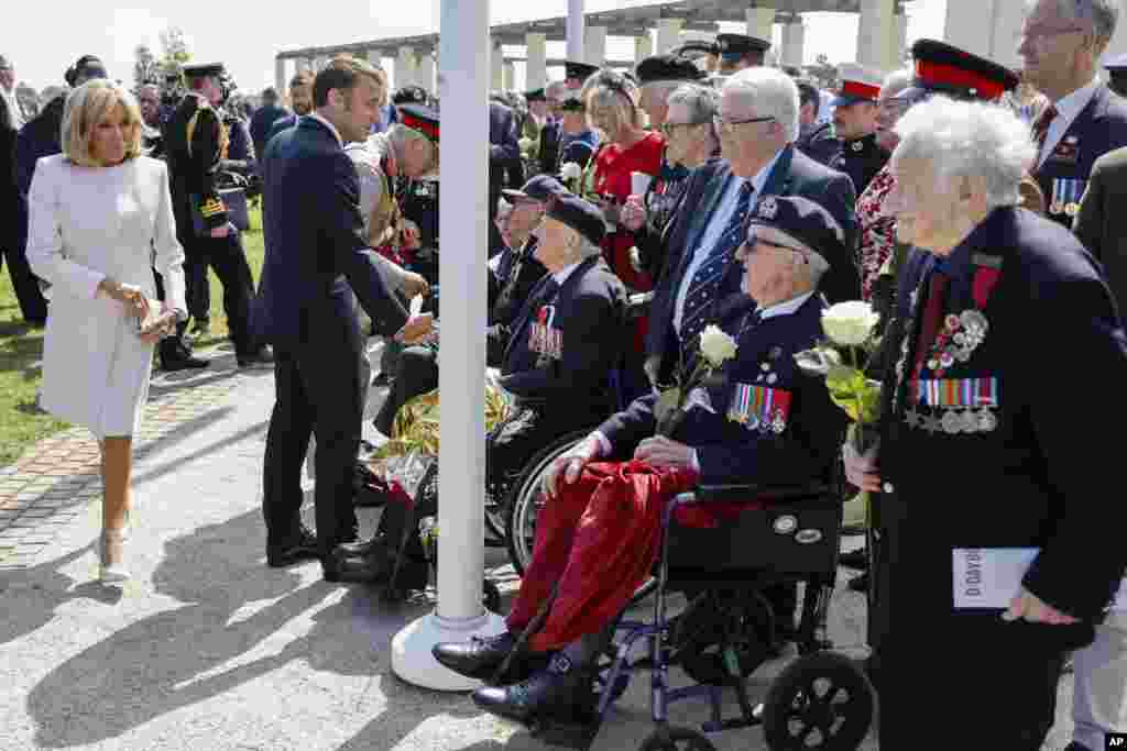 O Presidente francês Emmanuel Macron, a sua esposa Brigitte Macron, o rei Carlos III da Grã-Bretanha, na retaguarda, encontram-se com os veteranos britânicos do Dia D durante uma cerimónia comemorativa que marca o 80&ordm; aniversário do desembarque dos Aliados do Dia D na Normandia, no Memorial da Segunda Guerra Mundial Britânica da Normandia de Ver-sur-Mer, 6 de junho de 2024.