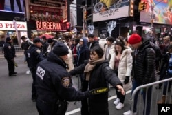 NYPD officers check people ahead of the New Year's Eve in Times Square celebration, Dec. 31, 2023, in New York.