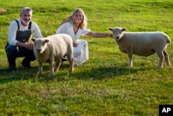 Jeff and Jamie Campion pose with their Southdown Babydoll sheep Buttermilk and Biscuit in their backyard in Thompson Station, Tennessee, July 3, 2024.