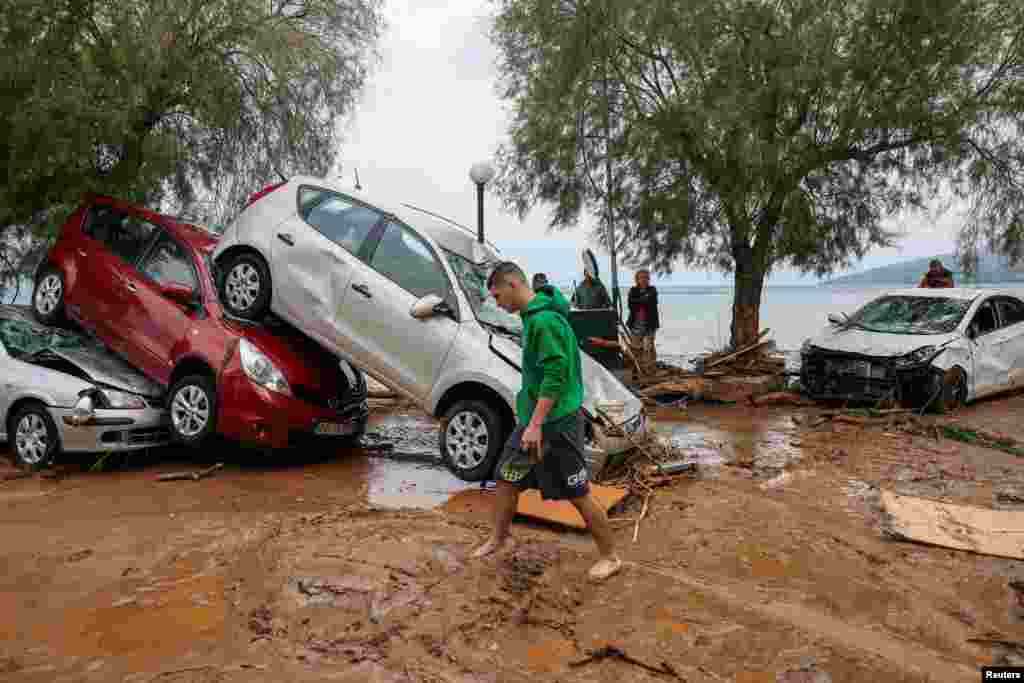 A local walks past damaged cars, as storm Daniel hits central Greece, in the village of Milina.