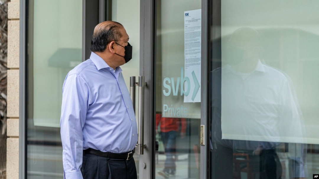 FILE - Attorney Randy Medina reads a notice posted on the door of a Silicon Valley Bank branch that reads, "FDIC Acts to Protect All Depositors of the former Silicon Valley Bank," in Pasadena, Calif., March 13, 2023.
