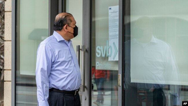 FILE - Attorney Randy Medina reads a notice posted on the door of a Silicon Valley Bank branch that reads,