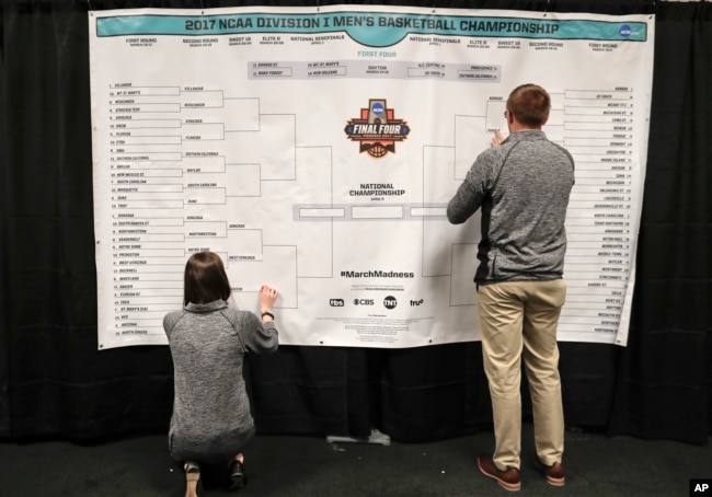 FILE - Staff members for the NCAA place the names of the teams in the Sweet 16 on a bracket in the media workroom before practices at the East Regional of the NCAA college basketball tournament in New York, March 23, 2017. (AP Photo/Julie Jacobson, File)