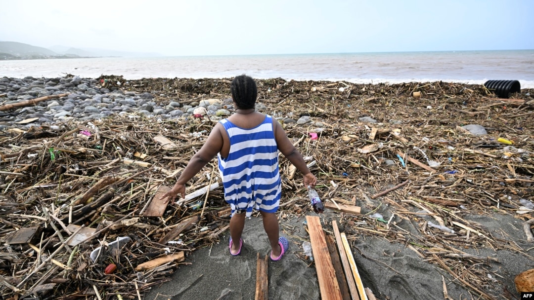 A woman looks at a beach littered with trash at Bull Bay, Jamaica, in the aftermath of Hurricane Beryl on July 4, 2024. 