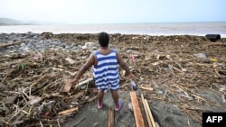 A woman looks at a beach littered with trash at Bull Bay, Jamaica, in the aftermath of Hurricane Beryl on July 4, 2024. 