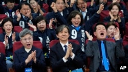 Cho Kuk, center, leader of the South Korean Rebuilding Korea Party, and his party members react as they watch a local media's results of exit polls for parliamentary election on television at the National Assembly in Seoul, South Korea, April 10, 2024.