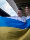 Ukrainian rapper alyona alyona, left, and singer Jerry Heil hold the Ukrainian flag as they pose for the media before departing from the main train station in Kyiv, Ukraine, April 25, 2024.