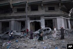 Palestinians walk amid the rubble following Israeli airstrikes that razed swaths of a neighborhood in Gaza City, Oct. 10, 2023.