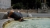 Seorang warga tampak membenamkan kepalanya ke dalam kolam air mancur di Piazza del Popolo di Roma, Italia, di tengah gelombang panas yang melanda pada 18 Juli 2023. (Foto: Reuters/Remo Casilli)