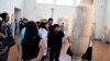 FILE - A group of Chinese tourists listen to a tour guide at the National Archaeological Museum in Athens, Greece, Aug. 3, 2017. 