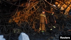 Officials walk through the rubble at the site following a fatal fire at a wedding celebration in the district of Hamdaniya in Iraq's Nineveh province, Sept. 27, 2023. 