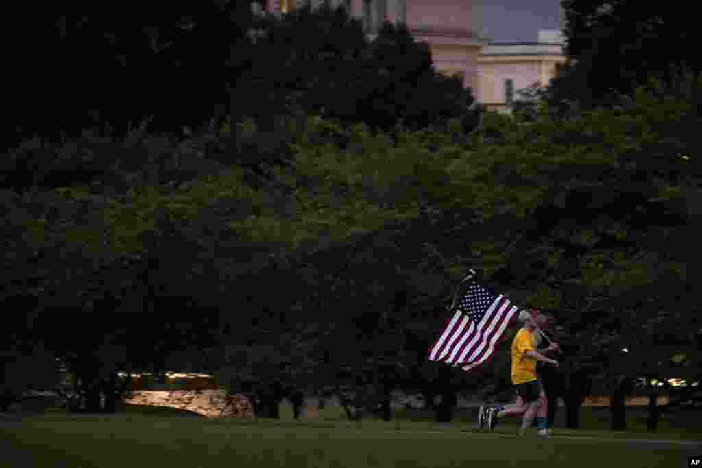 Runners carry an American flag as they jog past the Washington Monument at dawn in Washington, on the 22nd anniversary of the Sept. 11, 2001, terror attack.