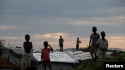FILE - Internally displaced people (IDPs) stand on roofs in the Protection of Civilians (POC) Camp, run by the UN Mission in South Sudan near the town of Malakal, in the Upper Nile state of South Sudan, Sept. 8, 2018.