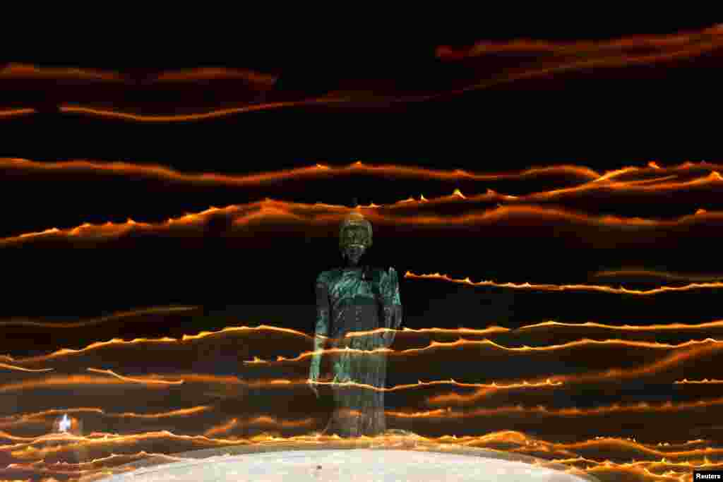 People walk with candle lights around a large Buddha statue during a ceremony commemorating Asalha Puja Day, an annual celebration marking the beginning of Triple Gem at a temple in Nakhon Pathom province on the outskirts of Bangkok, Thailand, July 20, 2024.&nbsp;