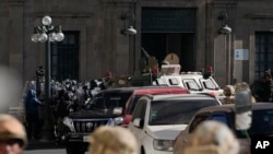 Policia ushtarake mblidhet përpara hyrjes kryesore të pallatit presidencial ndërsa një autoblindë hap me forcë portën kryesore (26 qershor 2024)