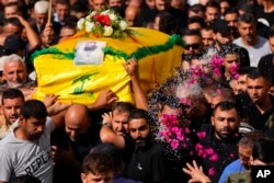 A woman throws rice and flowers as people carry the coffin of Hezbollah fighter, Bilal Nemr Rmeiti, who was killed by Israeli shelling, during his funeral procession in Majadel village, south Lebanon, Oct. 22, 2023.