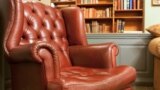Pictured here is an traditional style armchair in front of some bookshelves.