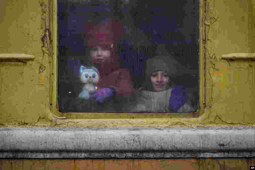 Дети смотрят из окна неотапливаемого поезда, следующего во Львов. Киев, 3 марта 2022. (AP Photo/Vadim Ghirda)