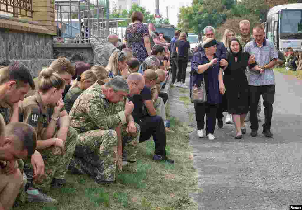 Relatives and friends react during a funeral ceremony for Ukrainian military pilots who were killed Tuesday when two helicopters crashed in Donetsk region, amid Russia's attack on Ukraine, at a wake in Poltava, Ukraine.