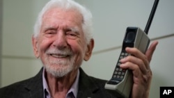 FILE - Martin Cooper, the inventor of first commercial mobile phone, poses with a Motorola DynaTAC 8000x during an interview with The Associated Press at the Mobile World Congress 2023 in Barcelona, Spain, Feb. 27, 2023. (AP Photo/Joan Mateu Parra)