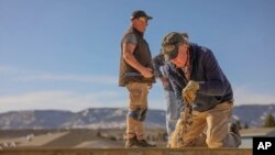 This April 2023 photo provided by Heart of Wyoming Habitat for Humanity shows volunteers from the organization working on construction projects in Casper, Wyoming, including framing, roofing, and painting.