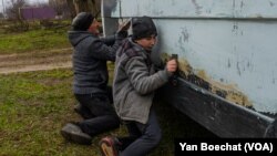 Family members scrub dark green paint off their vehicle after it was commandeered and later returned by the Ukrainian military on Jan. 26, 2023 in Pravdne, Ukraine.