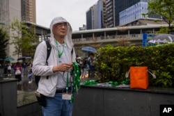 A protester waits for participants to distribute number tags prior to a rally in Hong Kong, March 26, 2023.