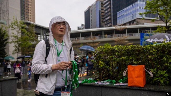 A protester waits for participants to distribute number tags prior to a rally in Hong Kong, March 26, 2023.