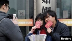 一对年轻人在北京一处婚姻登记处外手举结婚证留影。（2017年2月14日）
