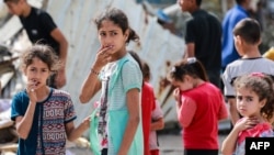 Palestinian children react next to the rubble of the Zaqout family's house hit during overnight Israeli bombardment in Nuseirat, in the central Gaza Strip, on May 30, 2024.