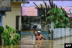 A man carrying his belongings wades through flood waters in Feni, Bangladesh, Aug. 23, 2024.