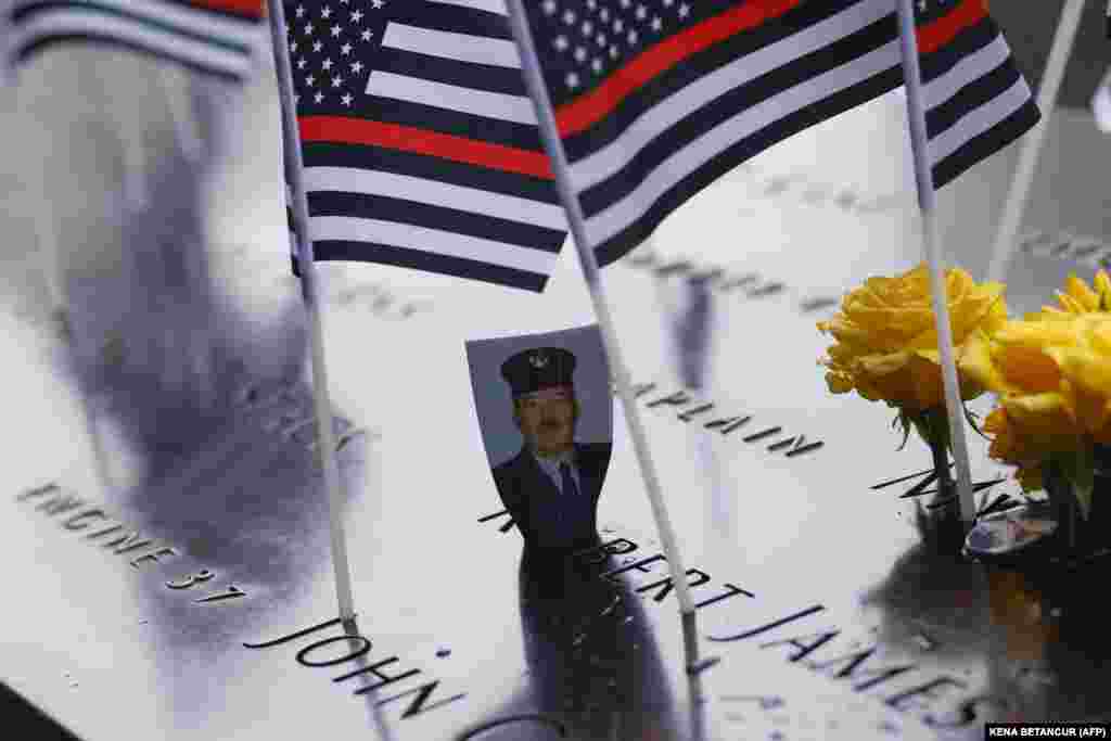 Uma fotografia é colocada na piscina do memorial do 11 de setembro, no 22.&ordm; aniversário do ataque terrorista ao World Trade Center, na cidade de Nova Iorque, a 11 de setembro de 2023. (AFP/KENA BETANCUR)