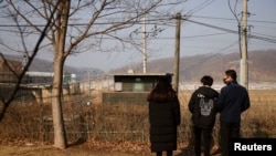 FILE - A North Korean defector and his children stand in front of a barbed wire fence near the demilitarized zone separating the two Koreas, in Paju, Feb. 12, 2021. 