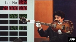 FILE - An auction house worker shows off Paul McCartney's 1964 custom Hofner 500/1 violin bass guitar during an internationally televised auction of the Beatles memorabilia collection in Tokyo, Japan, March 22, 1997.