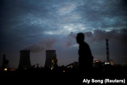 ภาพชายคนหนึ่งขณะเดินผ่านโรงไฟฟ้าพลังถ่านหินในนครเซี่ยงไฮ้ ประเทศจีน เมื่อวันที่ 14 ตุลาคม 2021 (REUTERS/Aly Song)