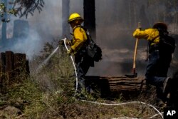 Vatrogasci gase žarišta iz požara u Parku u blizini Forest Rancha, Kalifornija, 30. jula 2024.