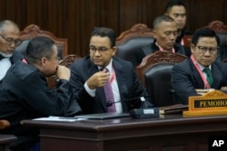 Calon presiden Anies Baswedan (tengah), dan pasangannya Muhaimin Iskandar, (kanan), berbincang dengan pengacaranya Ari Yusuf Amir saat sidang banding pemilu di Mahkamah Konstitusi di Jakarta, Senin, 22 April 2024. (AP/Dita Alangkara)